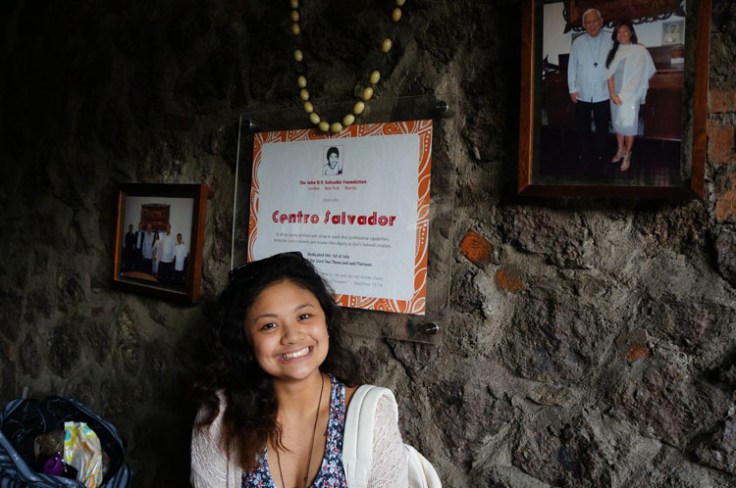Dana takes a picture in front plaque that thanks her relative Centro Salvador who is the biggest financial donor to this cause